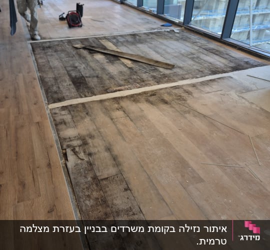 רצפת עץ חשופה עם סימני רטיבות ותיקון